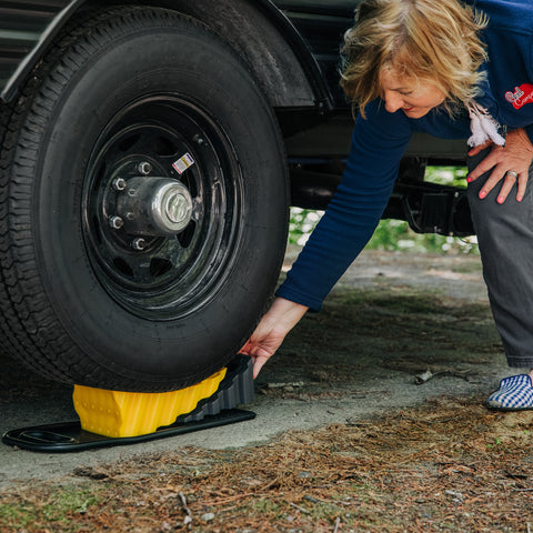 Woman Using Yellow Camco Wheel Chock - In-Use Application | United RV Parts